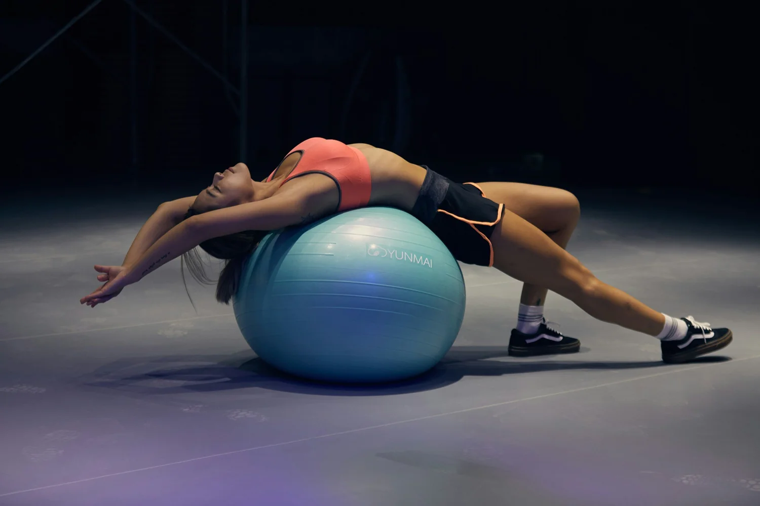 Person lying back over a large therapy ball with arms outstretched overhead to reverse the day’s forward-reaching posture