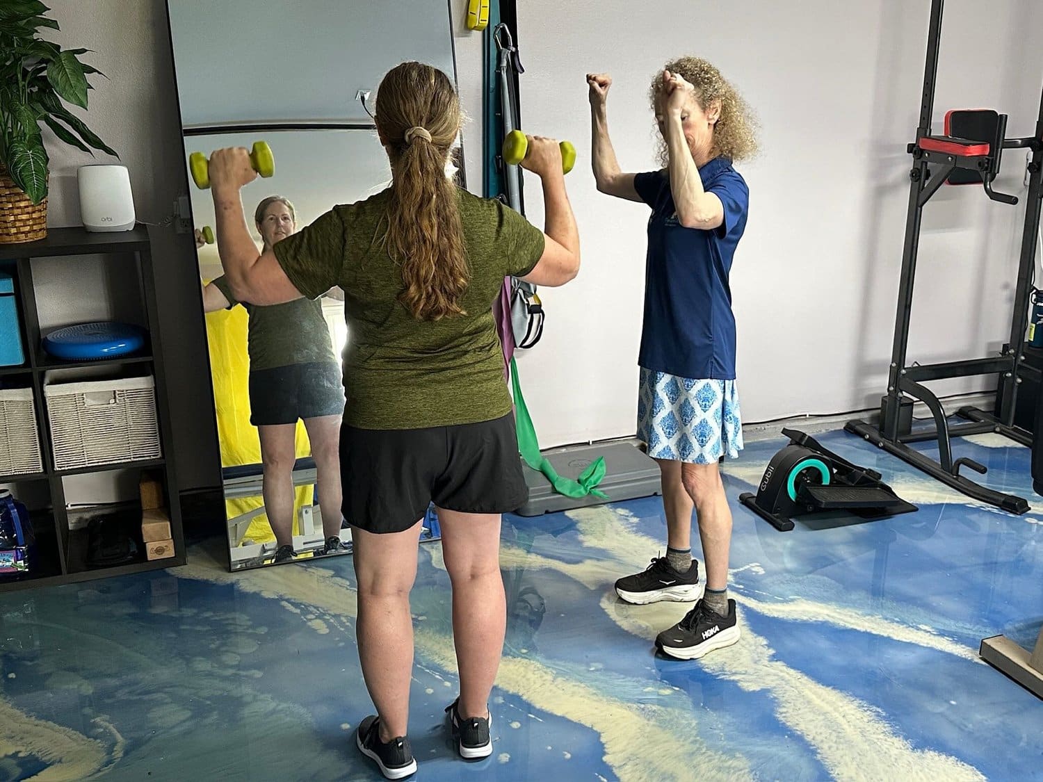 Two people working with dumbbells in front of the studio mirror