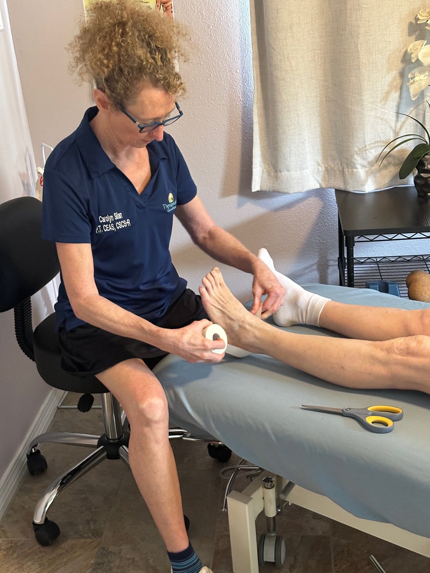 Therapist applying kinesiology tape to an ankle