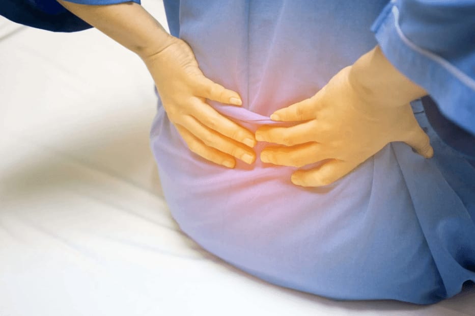 Person experiencing lower back pain, holding their lower back