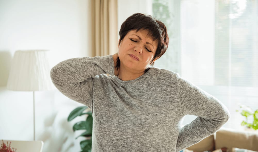 Woman experiencing neck pain, holding her neck