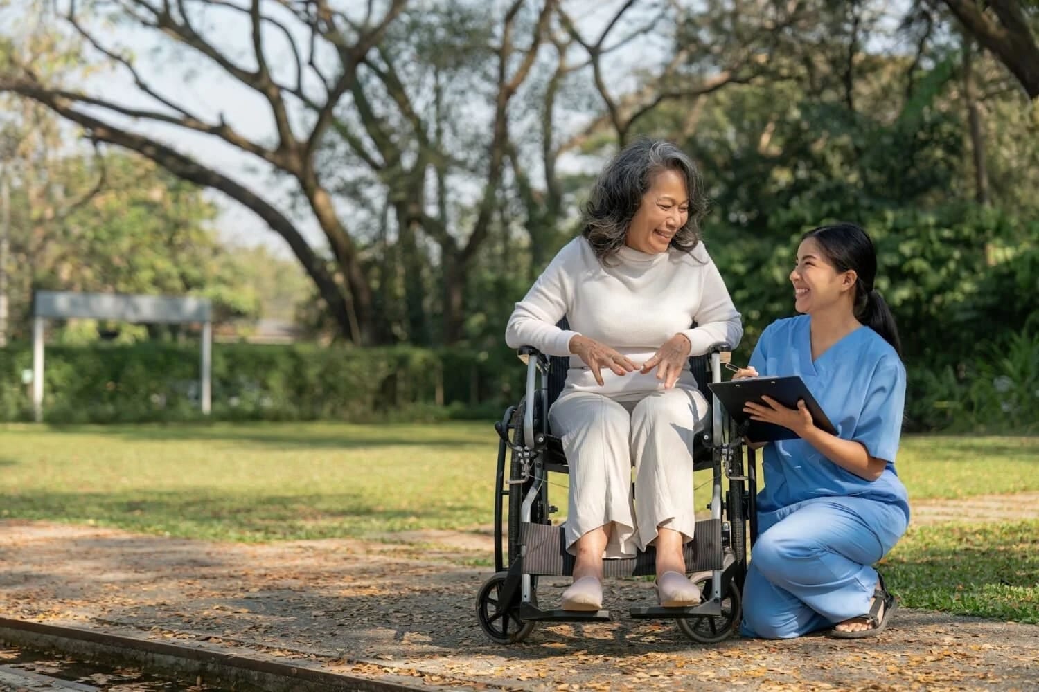 Caregiver assisting an elderly woman seated in a wheelchair