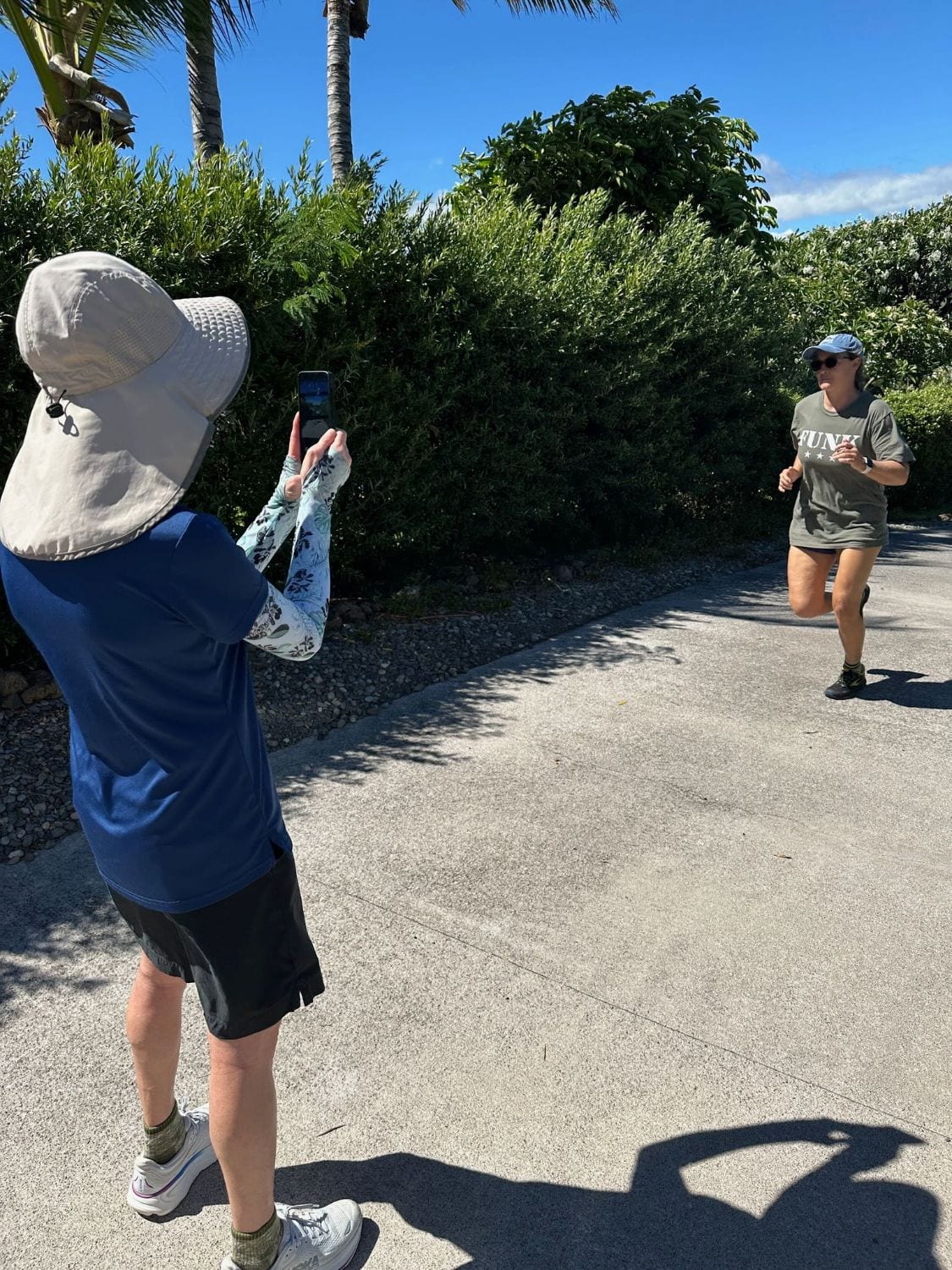 A running assessment outdoors: the therapist films a client running toward the camera along a paved path