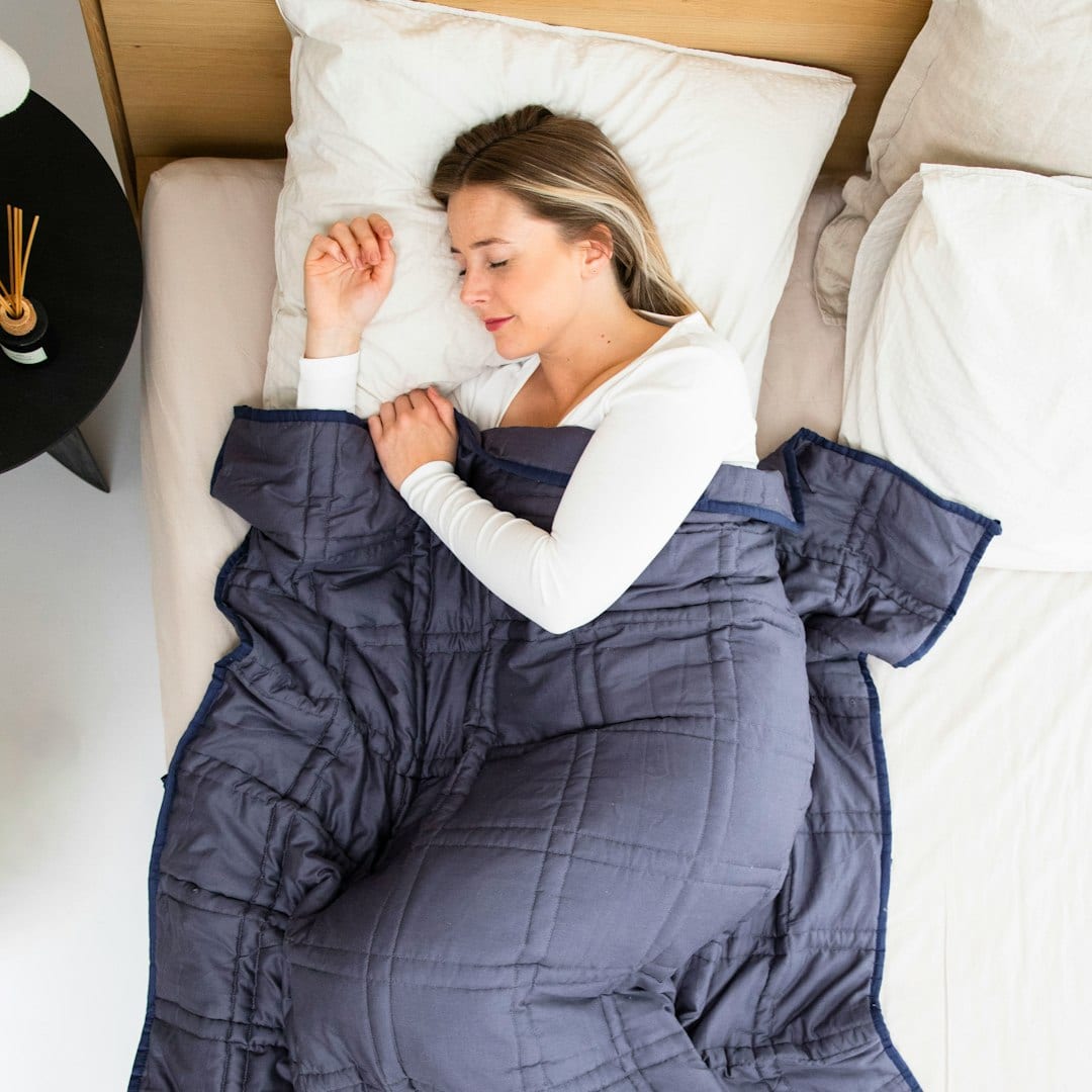 A woman sleeping peacefully on her side under a blue blanket